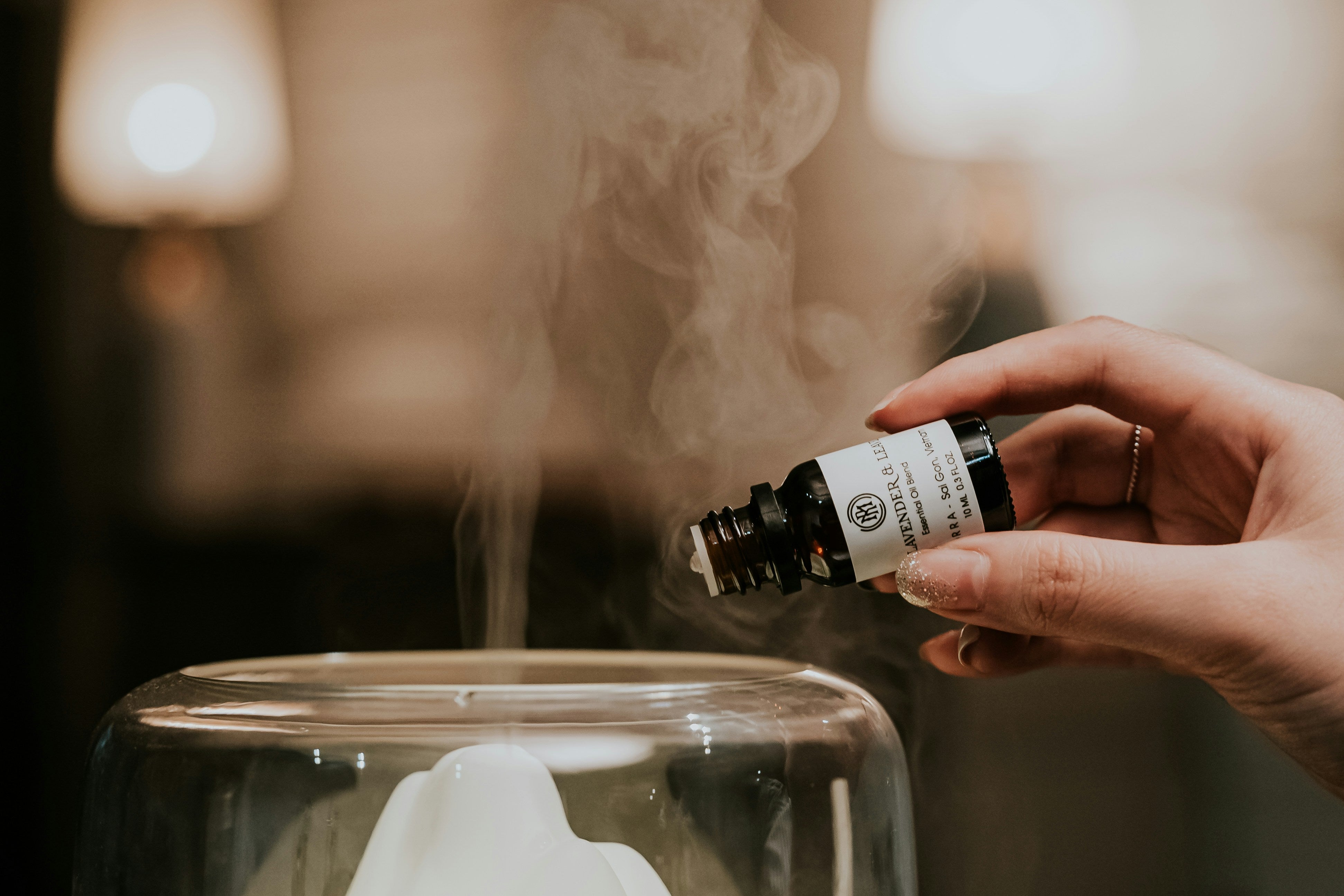 Female hand putting essential oils into a diffuser